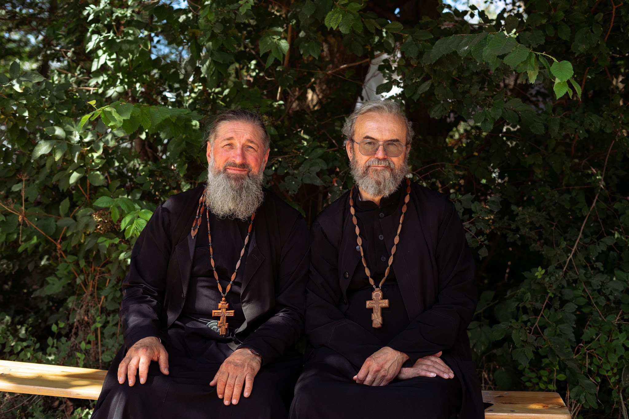 Priester Dimitri Jatsun (links) en priester Anatoli Babiouk (rechts) op een bankje op het kampterrein